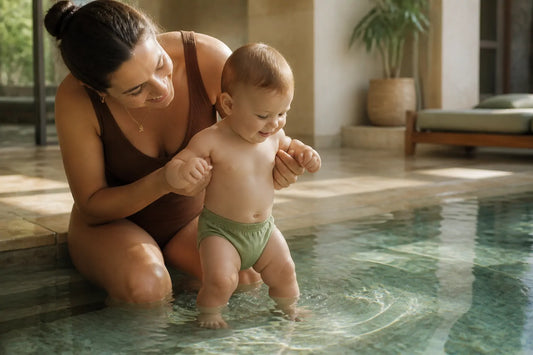 Bébé en couche de bain tenu au bord du bassin par son parent