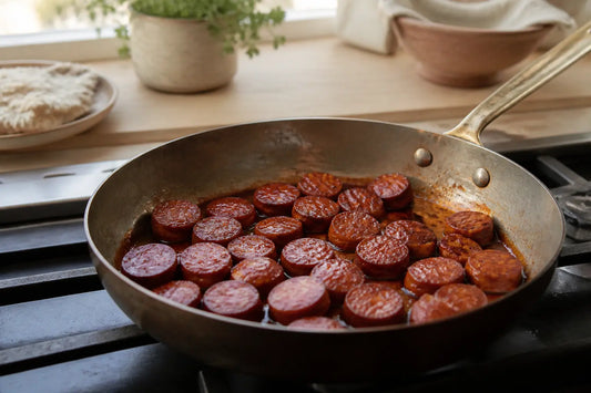 Chorizo cuit enceinte dans une poêle, en gros plan sur une cuisinière de cuisine, lumière naturelle douce.