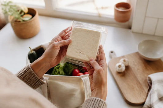 Main tenant un paquet de feta et lisant l’étiquette, contexte feta femme enceinte en cuisine, lumière douce naturelle