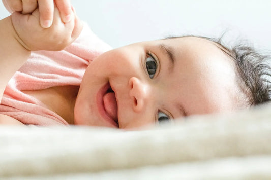 Bébé souriant allongé sur un textile blanc