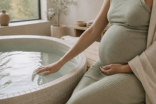 Jacuzzi enceinte : femme enceinte testant l’eau d’un jacuzzi dans une salle de bain spa lumineuse, vue rapprochée sur le ventre et la main.