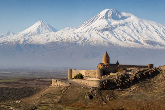 Monastère de pierre ancien sur un plateau avec des montagnes enneigées à l'arrière-plan