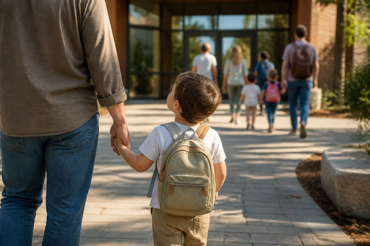 Tout-petit avec son sac à dos devant l'entrée de l'école