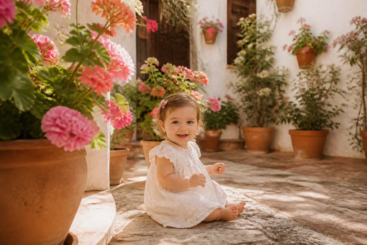 Bébé fille dans un patio espagnol fleuri de géraniums, lumière dorée